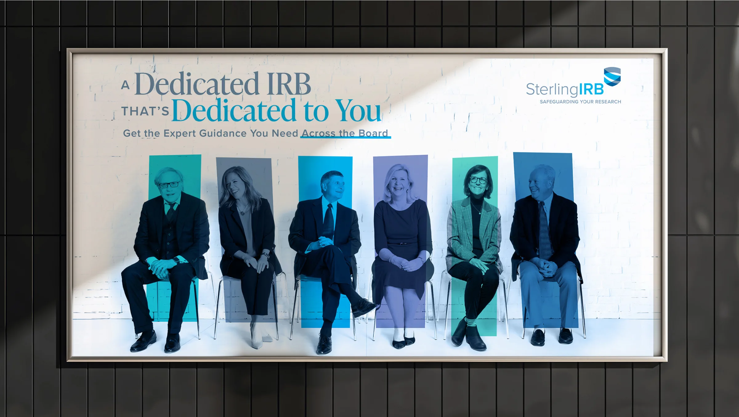 Sterling IRB brand image showcasing their 'big idea' of dedicated institutional review board (IRB) services. The billboard features six Sterling IRB team members seated in a row, each highlighted with a distinct blue-toned overlay. The headline reads, 'A Dedicated IRB that’s Dedicated to You,' emphasizing Sterling IRB’s commitment to expert guidance 'Across the Board.' The Sterling IRB logo is positioned in the upper right corner, reinforcing the message of dedication and trust in ethical research oversight.
