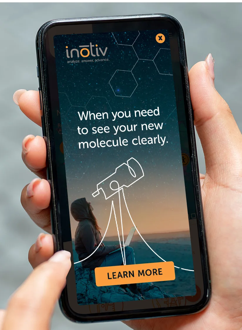 A close-up image of a smartphone held in a hand, displaying an ad with the text 'When you need to see your new molecule clearly.' The background shows a person sitting on a rock under a starry sky, gazing through a telescope. The Inotiv logo is visible at the top left, and a 'LEARN MORE' button is at the bottom of the screen. Molecular structures are subtly overlaid on the sky.