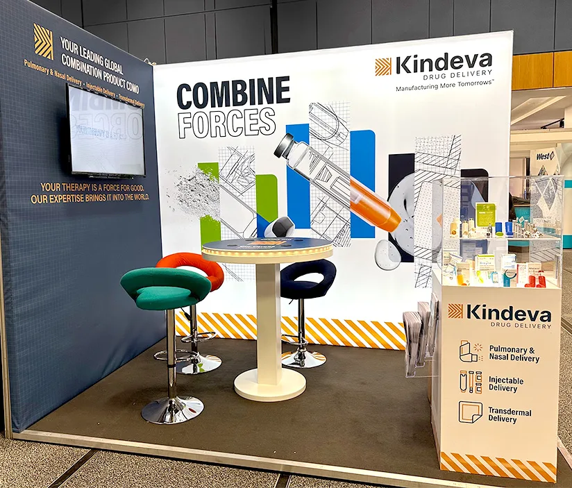 Kindeva Drug Delivery booth at the Drug Discovery to the Lungs (DDL) conference, featuring colorful chairs, a round table, a product display case, and a backdrop with the “Combine Forces” message and visuals of inhalation delivery devices.