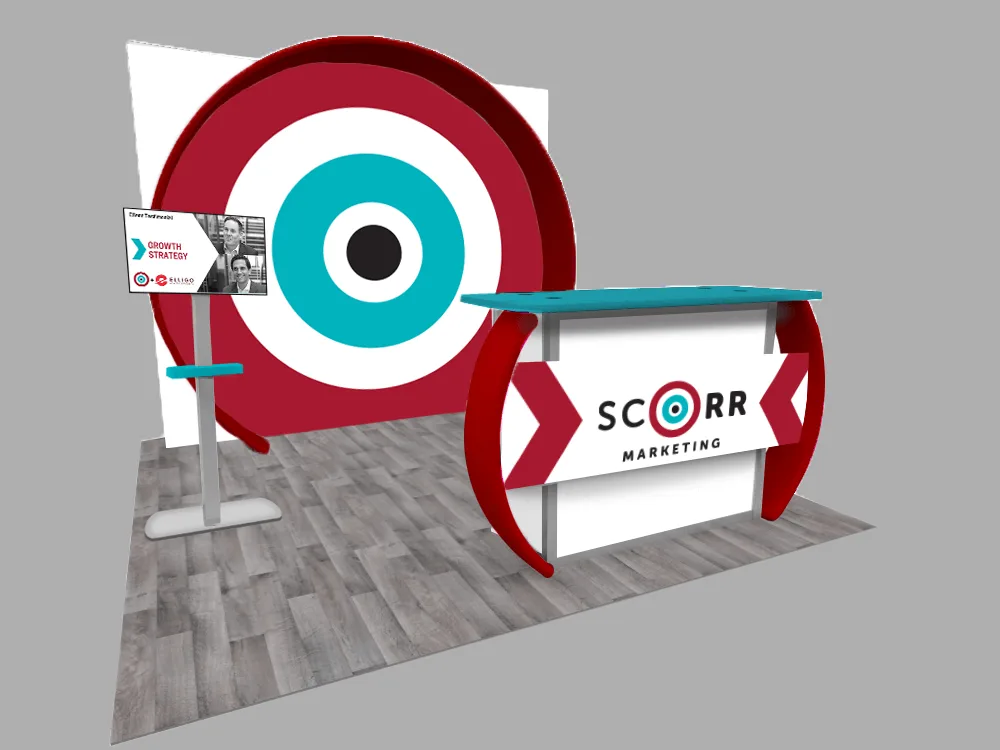 A vibrant 10x10 booth with a large bullseye backdrop, flat-screen testimonial display, and a branded SCORR Marketing counter. The flooring has a gray wood pattern.