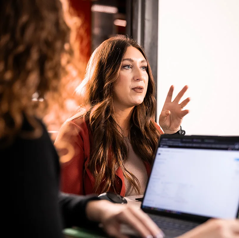 SCORR employee talking while another is on their computer.