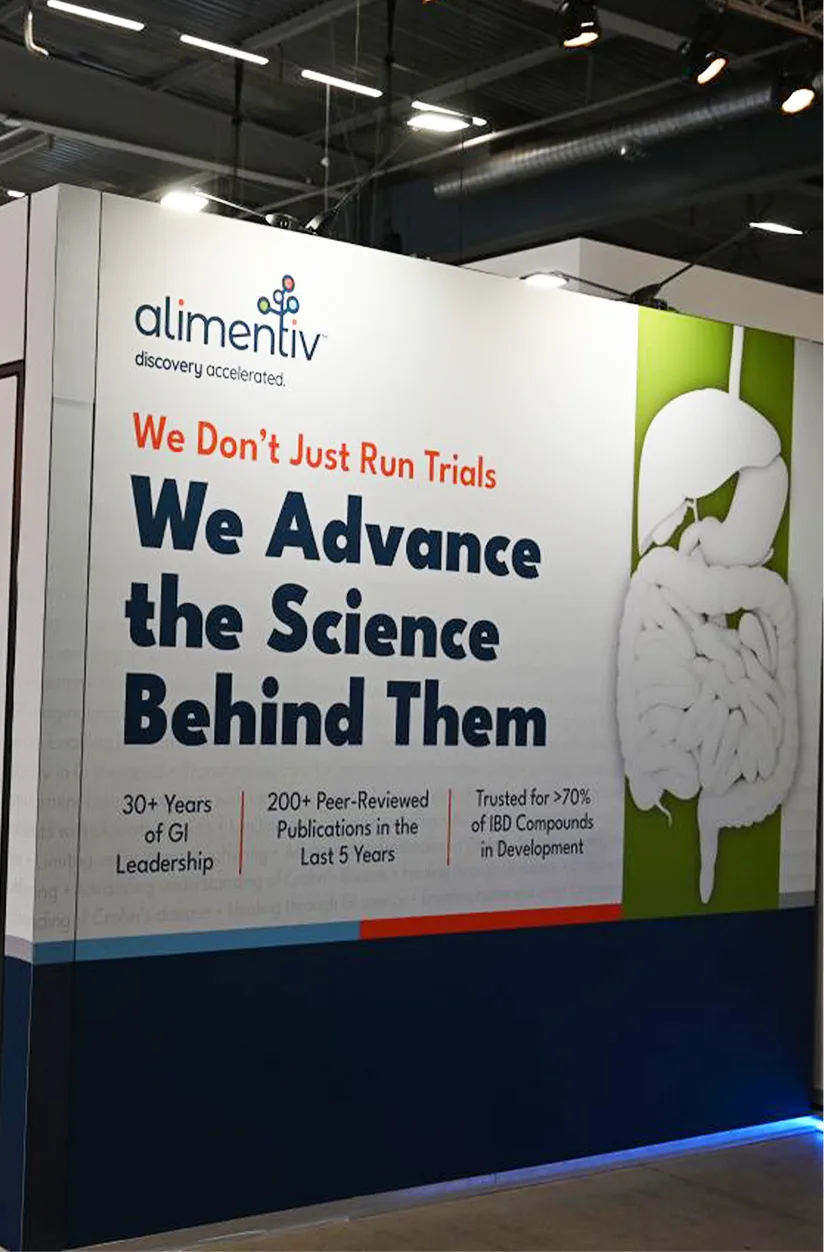 Alimentiv conference booth panel reading "We Advance the Science Behind Them," showcasing 30+ years of GI leadership and IBD trial expertise.
